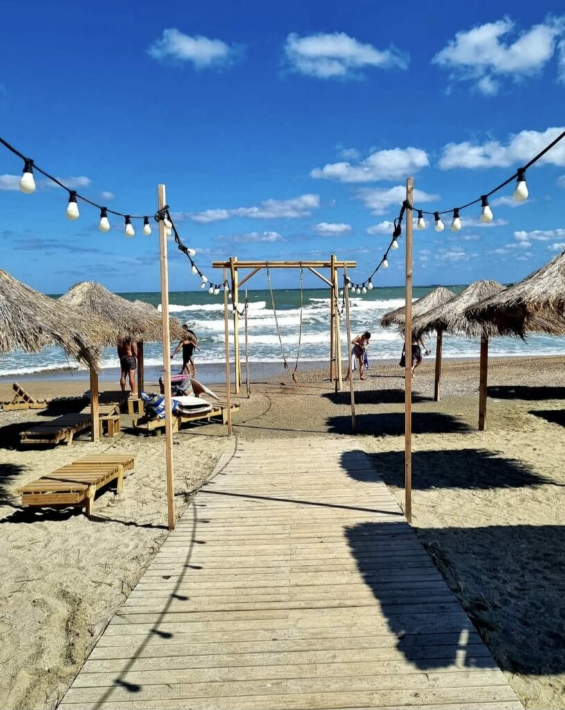 Alee de lemn pe plajă cu umbrele, simbol al turismului estival